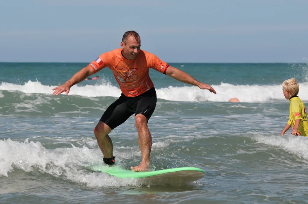 Adulte debout sur la planche de surf planche de surf sur une vague Côte Sauvage cours de surf de surf – ESCS La Palmyre Côte Sauvage