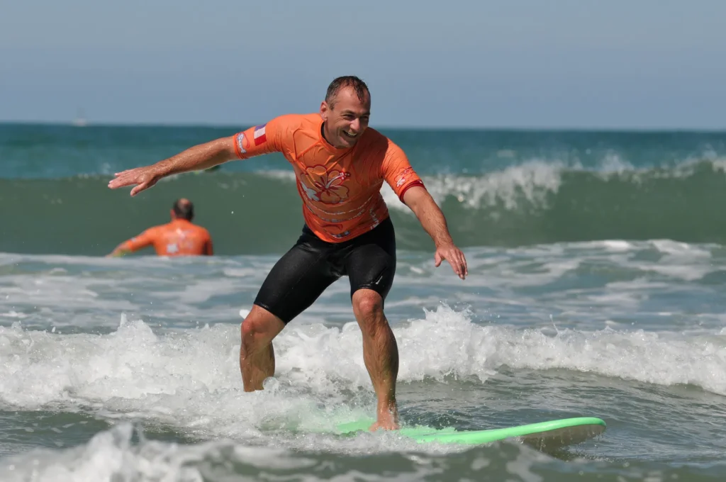 Adulte surf Côte Sauvage lycra orange sur une vague – ESCS La Palmyre Côte Sauvage