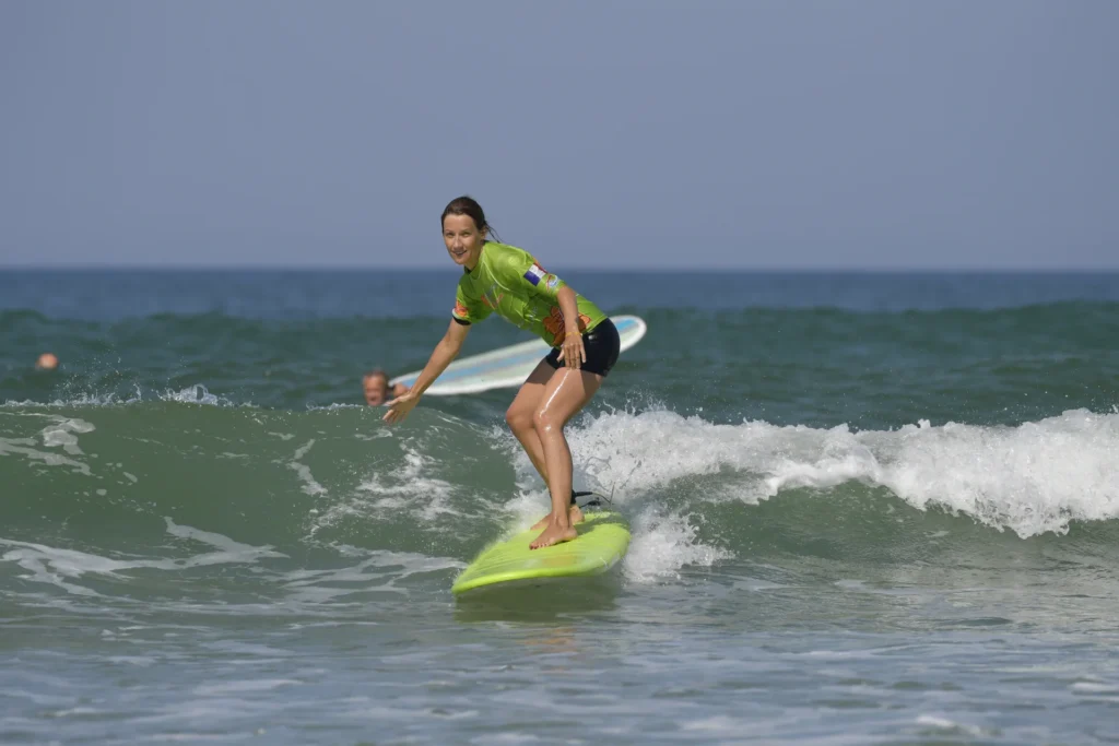 Cours de surf de surf femme debout sur la planche de surf sur une vague Côte Sauvage ESCS – ESCS La Palmyre Côte Sauvage