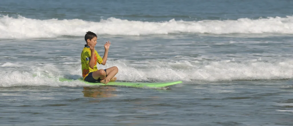Enfant assis planche de surf mousse sur les vagues Côte Sauvage – ESCS La Palmyre Côte Sauvage