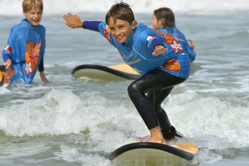 Enfant debout sur la planche de surf sur une vague cours de surf Côte Sauvage ESCS – ESCS La Palmyre Côte Sauvage