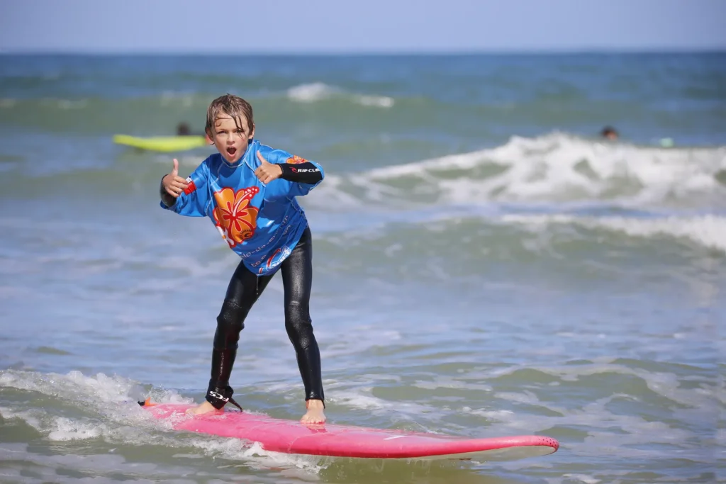 Enfant surf debout sur la planche de surf planche de surf Côte Sauvage La Palmyre – ESCS La Palmyre Côte Sauvage