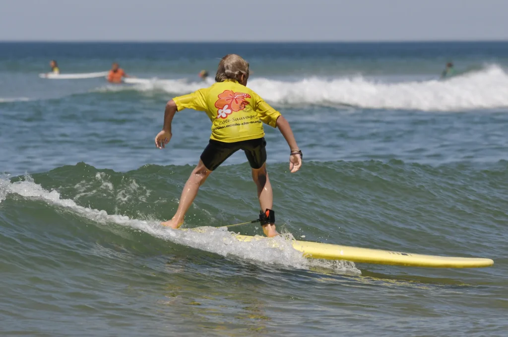 Enfant surf sur une vague Côte Sauvage ESCS lycra jaune – ESCS La Palmyre Côte Sauvage