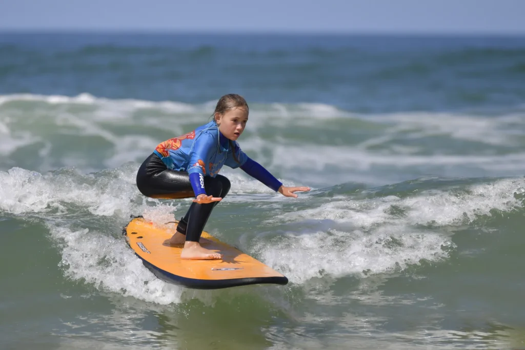 Jeune surfeuse en glisse sur une vague cours de surf de surf enfants Côte Sauvage – ESCS La Palmyre Côte Sauvage