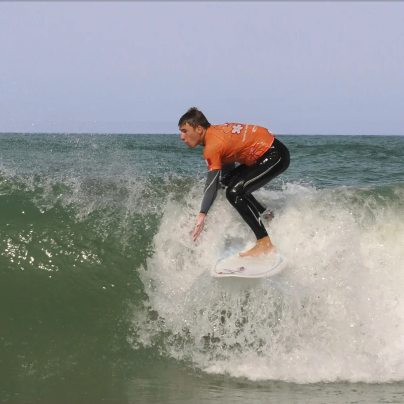 Surfeur lycra orange sur une vague Côte Sauvage La Palmyre – ESCS La Palmyre Côte Sauvage